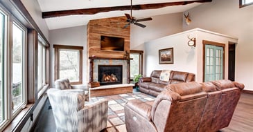 Open-concept living area in a whole home remodel by Fox Home Innovations with exposed beams, custom fireplace, ceiling fan, and large windows in Manhattan, KS