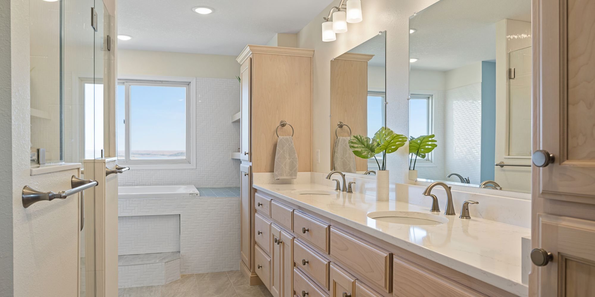 Bathroom remodel in Manhattan, KS with a dual-sink vanity, large shower, and built-in tub under a window by Fox Home Innovations