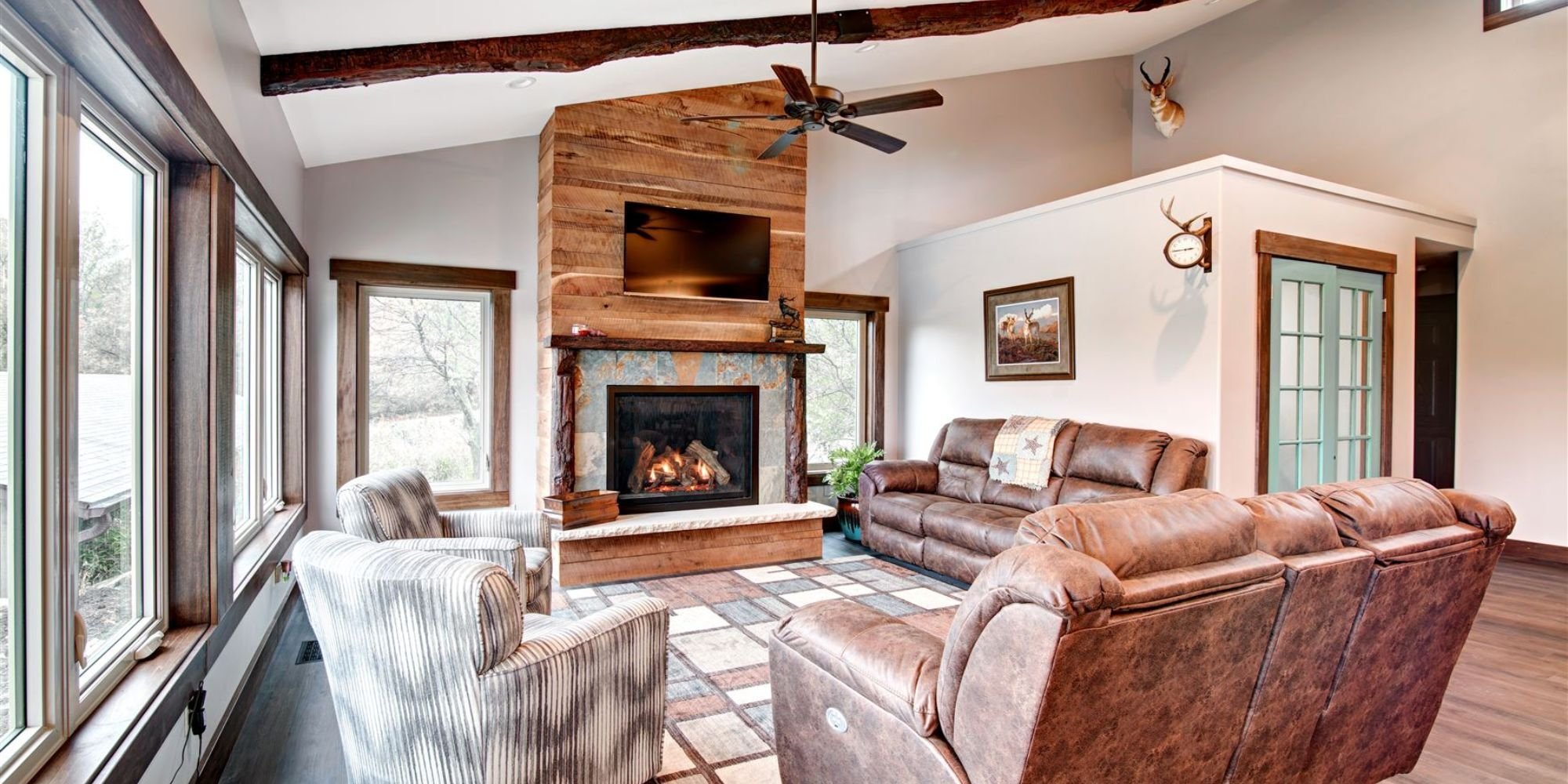 Open-concept living area in a whole home remodel by Fox Home Innovations with exposed beams, custom fireplace, and large windows in Manhattan, KS