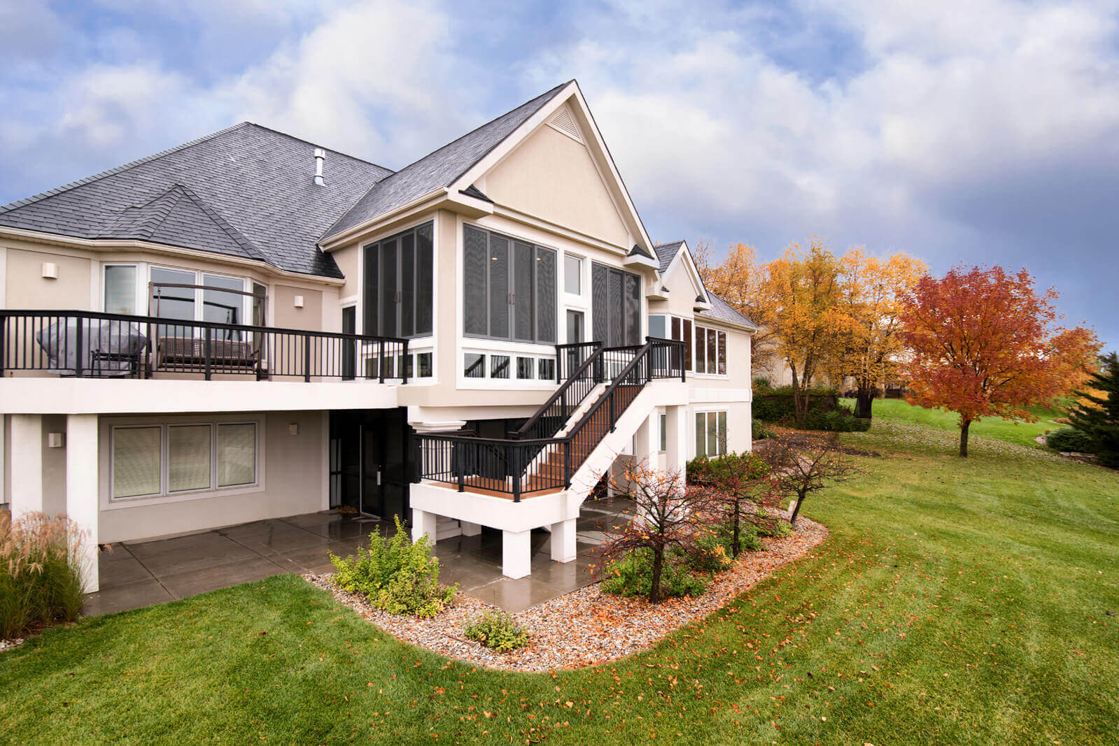 Exterior of a remodeled home with a second-story deck and new staircase with a landing and black metal railing by Fox Home Innovations in Manhattan, KS