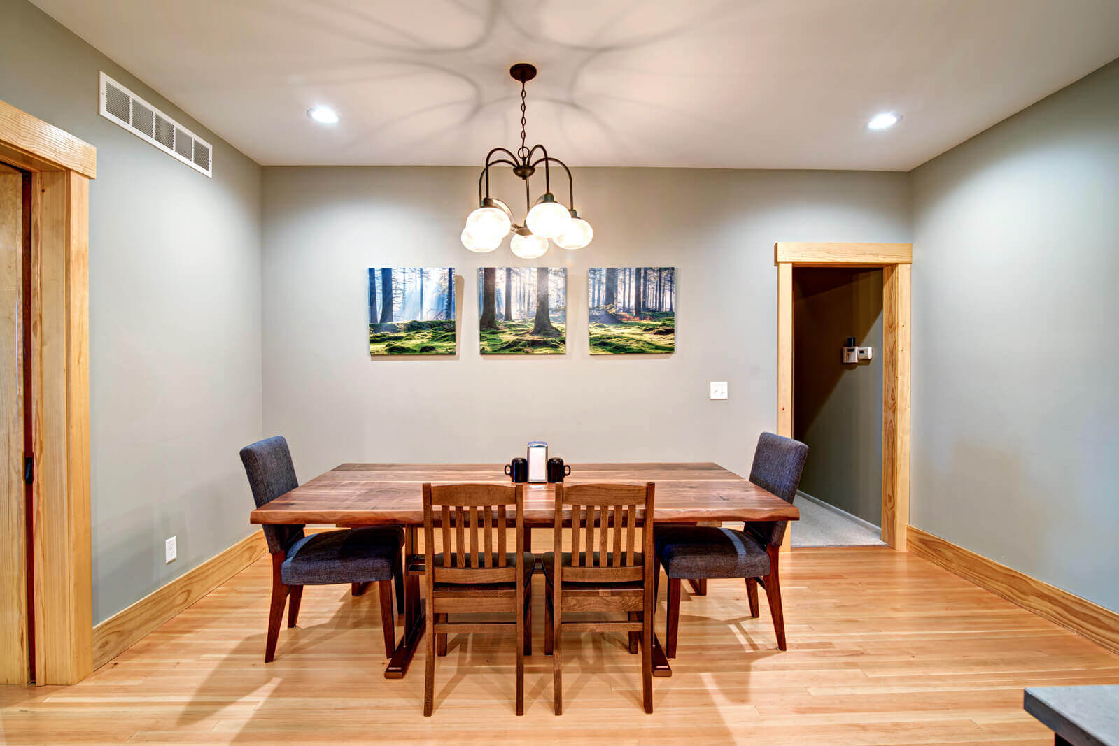Remodeled dining room in Manhattan, KS with hardwood floors, wood trim, and a chandelier above the dining table by Fox Home Innovations