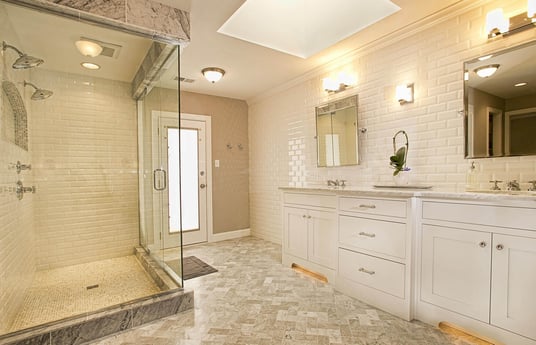 modern bathroom remodel with large glass shower door and white cabinets